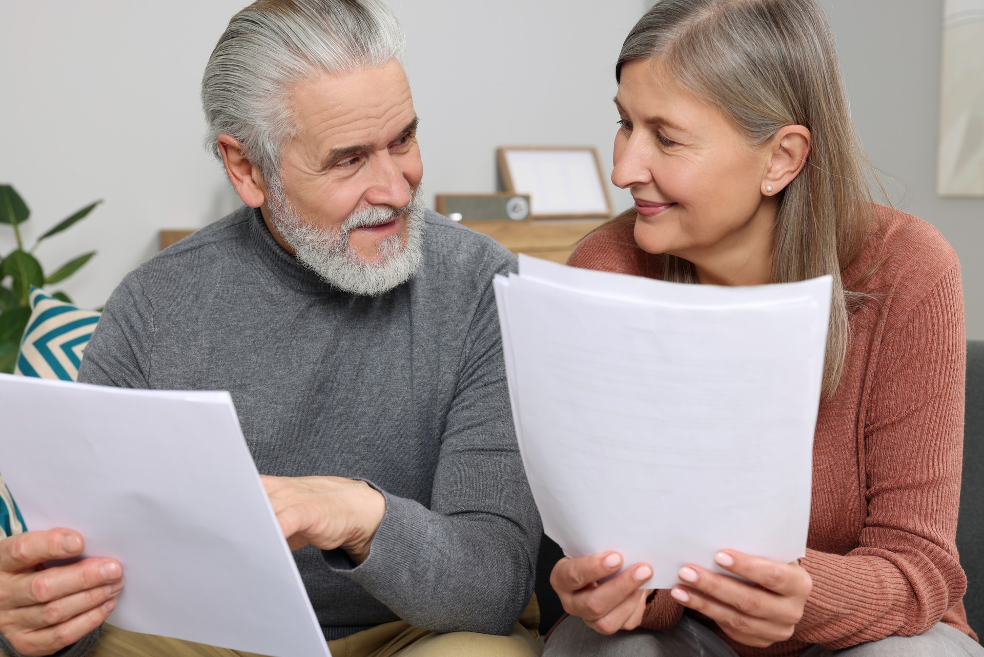 Elderly couple with papers discussing pension plan in room